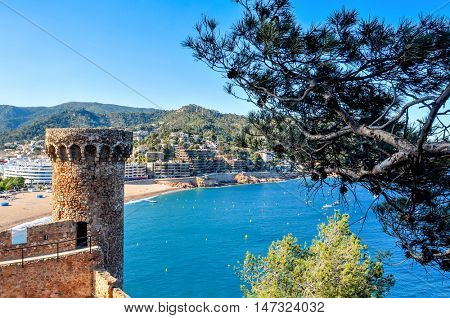 a view of the walls and towers of the Vila Vella, the old town, of Tossa de Mar, Spain with the Platja Gran beach in the background