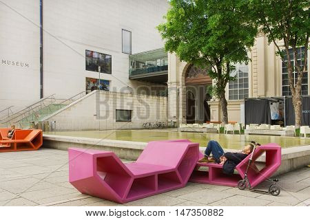 VIENNA, AUSTRIA - JUN 10, 2016: Man having rest in outdoor bench in modern style near Leopold Museum on June 10, 2016. Museum has largest collections of Austrian art featuring Egon Schiele Gustav Klimt