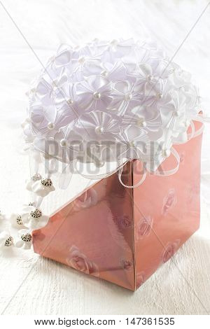Homemade beautiful bow with pendants in the art kanzashi for decoration gifts. Are fixed on the gift box. White wooden background