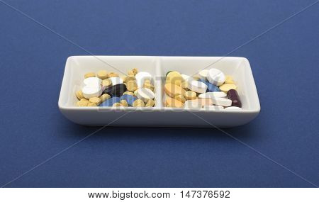 Different Capsule and tablets in plate on blue background.