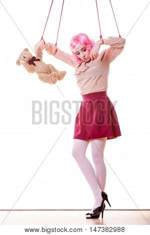 Mental disorder concept. Young woman girl stylized like marionette puppet on string with teddy bear toy isolated on white background