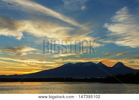 Beautiful sunrise over the volcanoes Kluchevskaya group with reflection in the river Kamchatka.