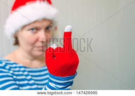Woman with Christmas Santa Claus hat giving middle finger rude gesture of serious and angry person selective focus