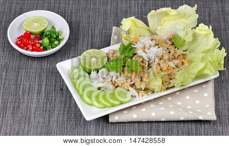 Fried rice with crab topped streamed crab,halve green lemon,sliced cucumber,lettuce and coriander served  spicy  sour filling side dish. Side view.