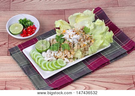 Fried rice with crab topped streamed crab,halve green lemon,sliced cucumber,lettuce and coriander  served  spicy  sour filling side dish  on wood. Side view.