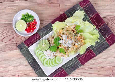Fried rice with crab topped streamed crab,halve green lemon,sliced cucumber,lettuce and coriander  served  spicy  sour filling side dish  on wood.  Top view