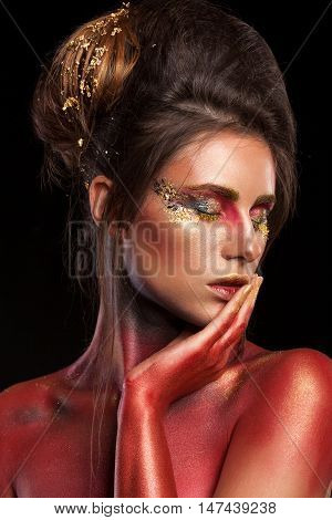 Creative make up with glitter gold and red colors on black background in studio photo. On stage and art beauty make up