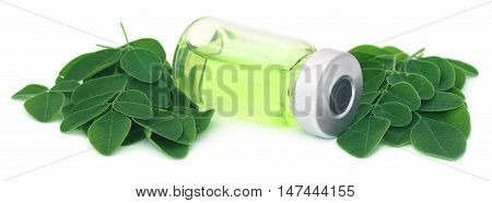 Moringa leaves with extract in a vial over white background