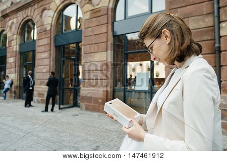 PARIS FRANCE - SEPTEMBER 16 2016: Woman in front of Apple Store looking at the New Apple iPhone 7 Plus box right after purchase on the date of worldwide launch. being tested by woman after purchase. New Apple iPhone tends to become one of the most popular