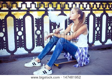 Elegant woman smoking e-cigarette with smoke wearing suit and hat
