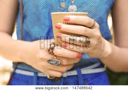 Close up of female hands with beautiful bijouteries holding cup of coffee