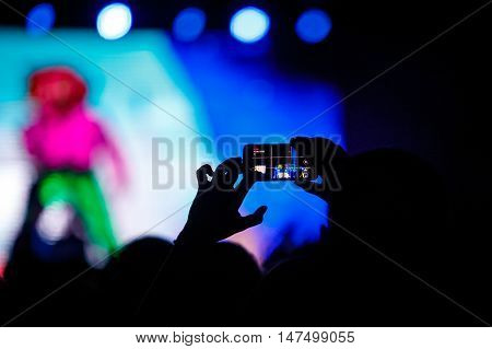 People makes photo with His smartphone on rock concert to share the moment with friends on social networks