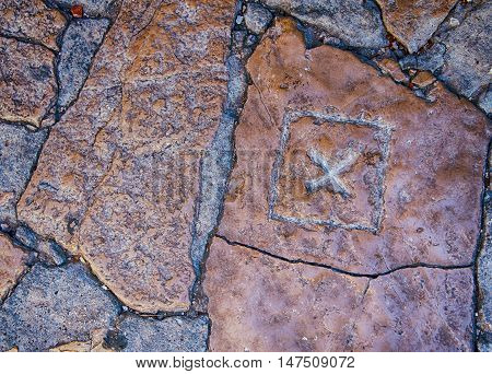 X mark carved in old stone pavement.