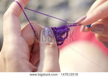 The Woman Knits Earrings In The Shape Of A Flower