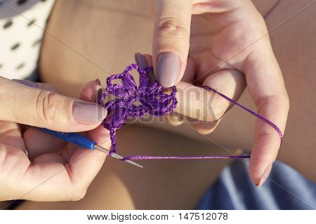 The Woman Knits Earrings In The Shape Of A Flower