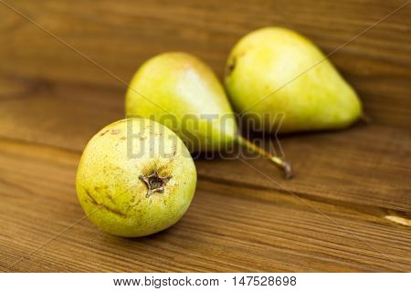 There are some yellow pears are on the wooden table