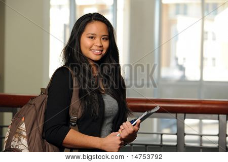 Retrato de niña filipina con portátil y mochila en interiores