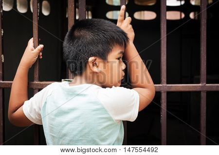 cute little asian  boy sad and hand hold jail