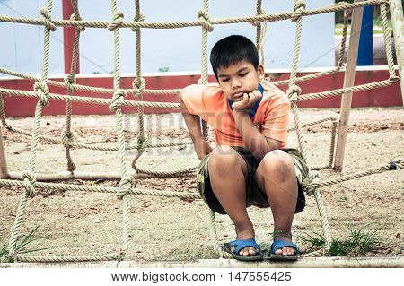 asian boy sitting alone at playground vintage tone