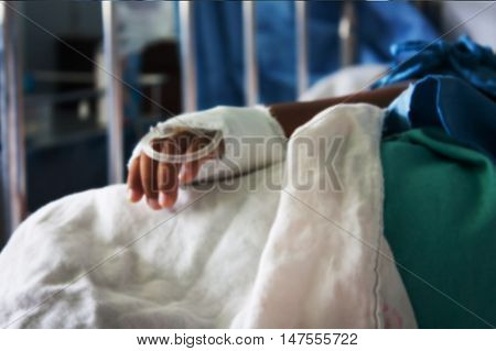 blurry of Hand of The Patient on the bedlittle boy sick in the Hospital with saline intravenous (iv)