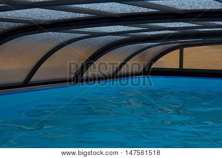 Inside of the outdoor swimming pool covered by roof construction. Private swimming pool with nobody around.
