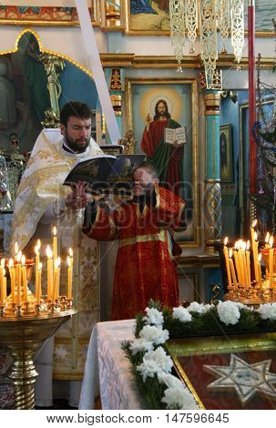 VOYUTYN UKRAINE - JANUARY 08: Orthodox priest and little sextons during holiday prayers in Voyutyn on January 08 2009.