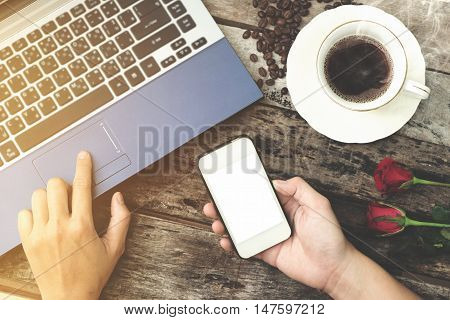 Coffee cup with hand using laptop and Mobile phone on old wood background