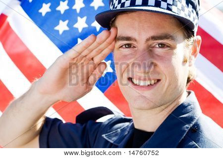 mladý americký policista zdravení, pozadí je vlajka USA