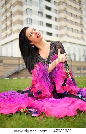Young woman in beautiful skirt zingara poses on lawn near building