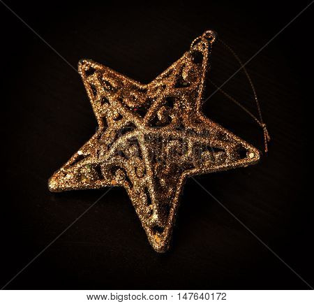 Golden artistic christmas star on the dark background. Christian holiday. Symbolic object.