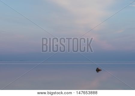 Evening sunlight on coast pink clouds blue sky reflection on water. Beach in summer. Seaside natural environment. Shore in Osmussaar Island Nature Reserve in Estonia National Park in Europe