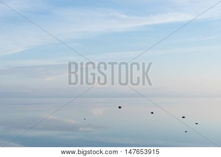 Evening sunlight on coast pink clouds blue sky reflection on water. Beach in summer. Seaside natural environment. Shore in Osmussaar Island Nature Reserve in Estonia National Park in Europe
