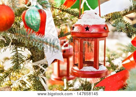 snow-covered fir tree decorated with red candlestick toys and tapes