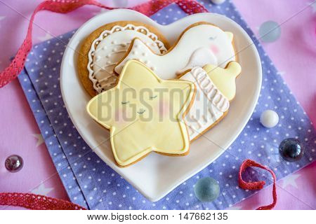 Baby glazed cookies in heart shape plate on decorated table