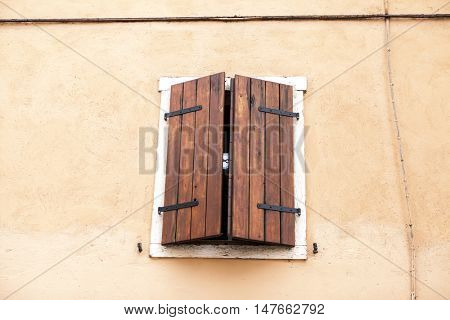 Old window with closed shutters with flowers on the window sill on the stone wall. Italian Village.