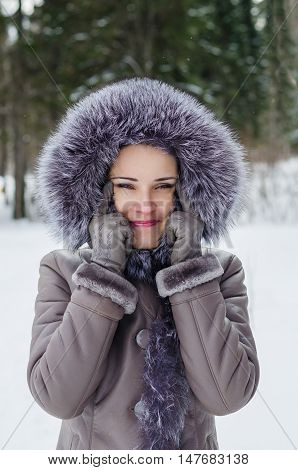 Beautiful woman in winter jacket with fur hood having fun making a funny face with Asian eyes