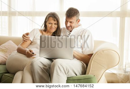 middle aged couple looking at a computer and smile