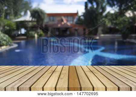 Wooden board empty table against of blurred swimming pool background,Perspective brown wood over swimming pool can be used for display or present your products,Mock up your products