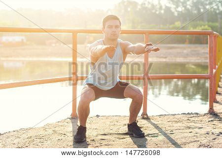 Fit man working out glutes with bodyweight workout doing squat exercises