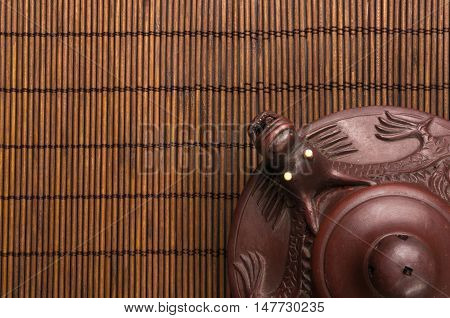 brown Chinese teapot of Yixing clay with traditional ornament on bamboo Mat