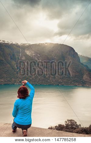 Tourism and travel. Woman tourist taking photo with camera enjoying mountains fjords view in Sogn og Fjordane county. Norway Scandinavia.