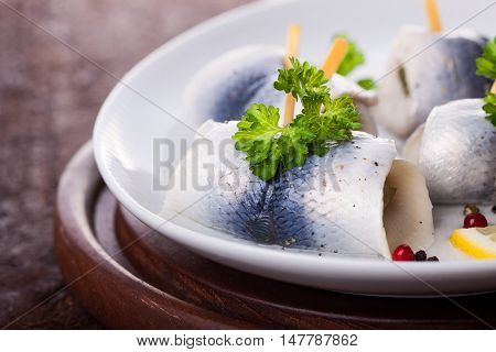 Rollmops (rolled marinated herring) with marinated cucumber salt pepper and parsley closeup