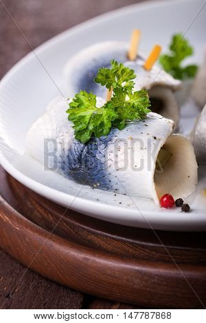 Rollmops (rolled marinated herring) with marinated cucumber salt pepper and parsley closeup