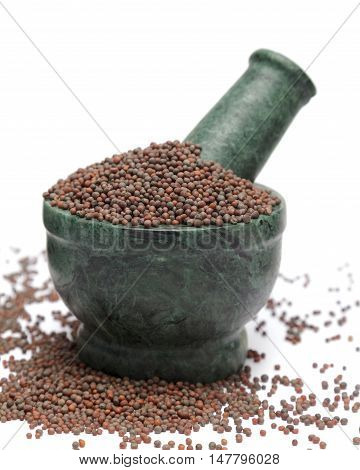 Organic Brown Mustard (Brassica juncea) on marble pestle and over white background.