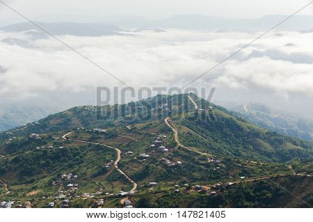 Clouds mist moves through rural valley hills covering homes over scenic landscape.