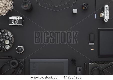 Work space on black table of a creative designer or photographer with laptop tablet camera and other objects of inspiration and copy space. Stylish home studio concept of technology trends.
