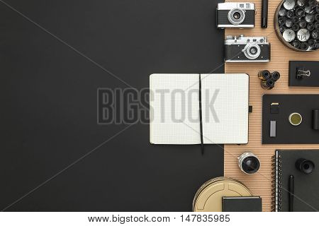 Work space on black table of a creative designer or photographer with laptop tablet camera other objects of inspiration and copy space. Stylish home studio concept of technology trends.