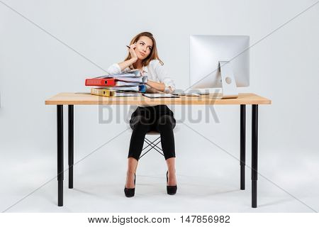 Full length portrait of concentrated pensive businesswoman thinking about something holding pen isoltaed on the white background