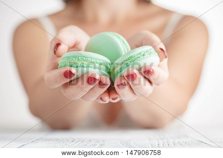 Woman holding few macaroons in both hands