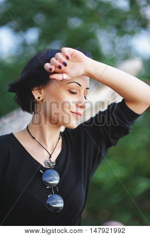 Beautiful black-haired girl wearily closing his eyes leaned my head against his raised hand in the Park on a summer day.